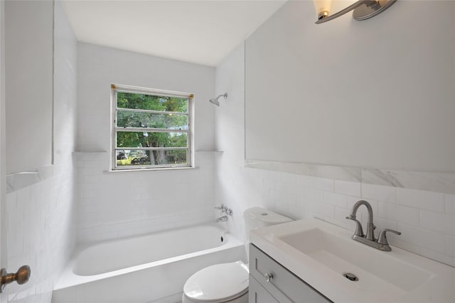 full bathroom with vanity, toilet, tiled shower / bath, and tile walls