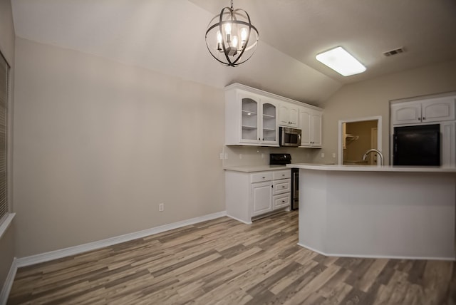 kitchen featuring white cabinetry, a notable chandelier, stove, refrigerator, and vaulted ceiling