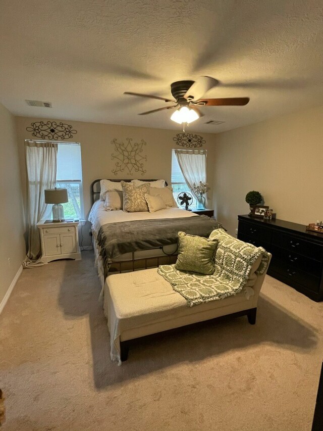 bedroom with carpet, a textured ceiling, and ceiling fan