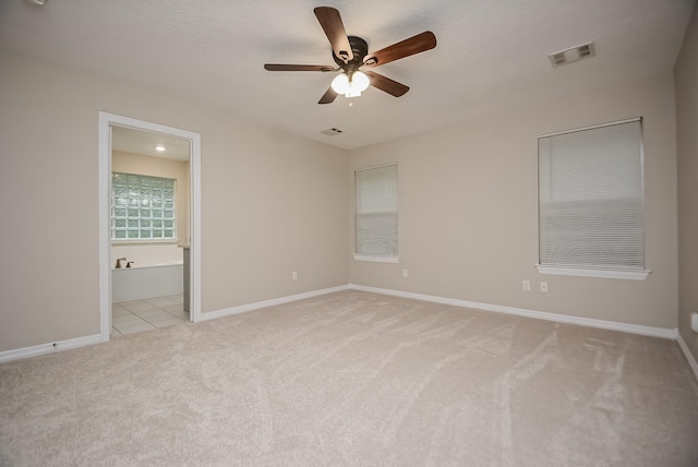 unfurnished bedroom with light carpet, ensuite bath, and ceiling fan