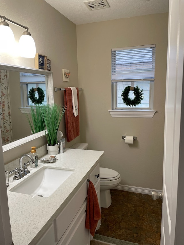 bathroom with vanity, toilet, and a textured ceiling