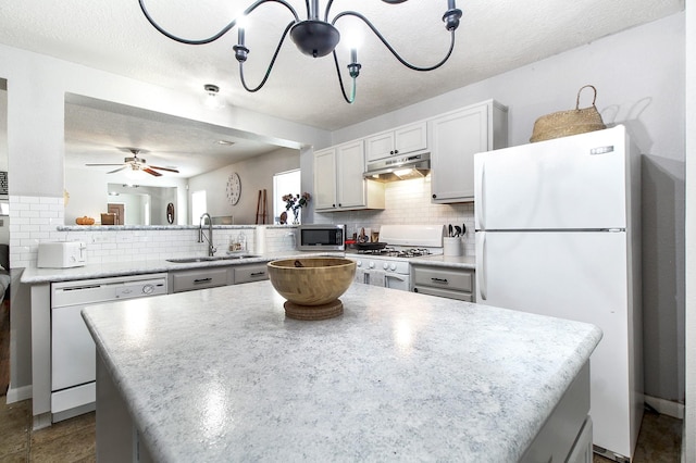 kitchen with kitchen peninsula, a textured ceiling, white appliances, sink, and white cabinets