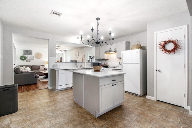 kitchen featuring white cabinetry, a center island, kitchen peninsula, white appliances, and ceiling fan with notable chandelier