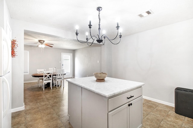 kitchen featuring ceiling fan with notable chandelier, white fridge, a kitchen island, and hanging light fixtures