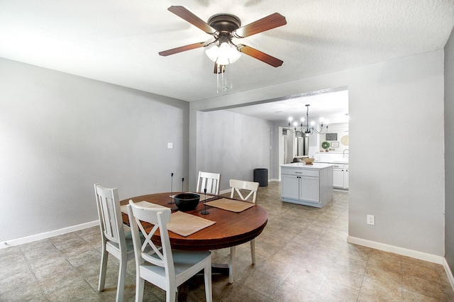 dining area featuring a textured ceiling, sink, and ceiling fan with notable chandelier