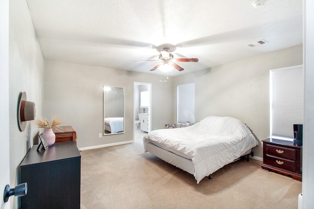 bedroom with light carpet, a textured ceiling, ensuite bath, and ceiling fan