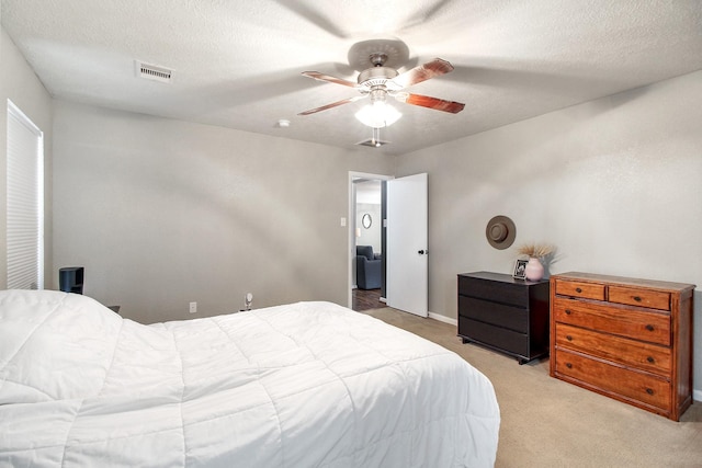 bedroom featuring ceiling fan, light colored carpet, and a textured ceiling