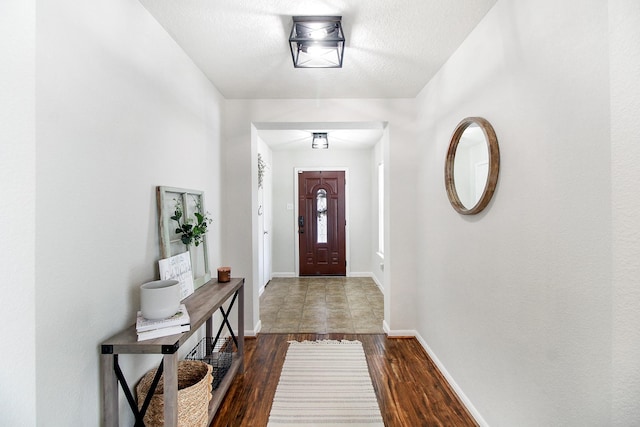 foyer entrance with a textured ceiling and dark wood-type flooring