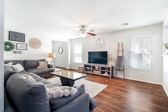 living room featuring ceiling fan, dark wood-type flooring, and a textured ceiling