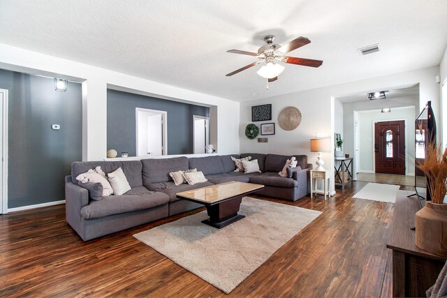 living room with dark hardwood / wood-style floors, ceiling fan, and a textured ceiling