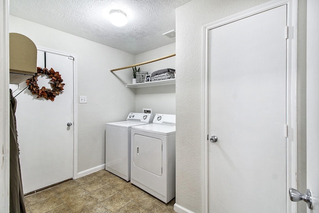 washroom with washer and clothes dryer and a textured ceiling