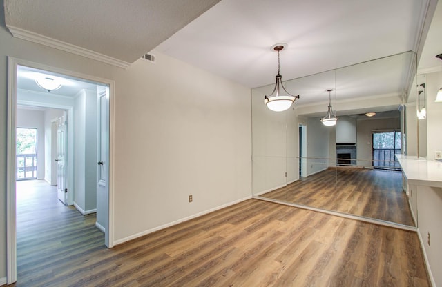 interior space with pendant lighting, ornamental molding, and wood-type flooring