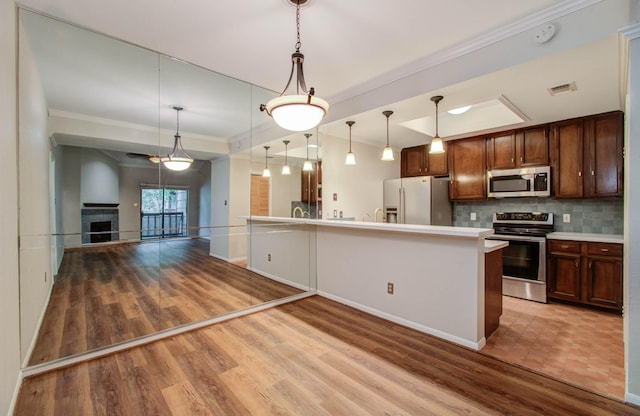 kitchen featuring hardwood / wood-style floors, hanging light fixtures, appliances with stainless steel finishes, and tasteful backsplash