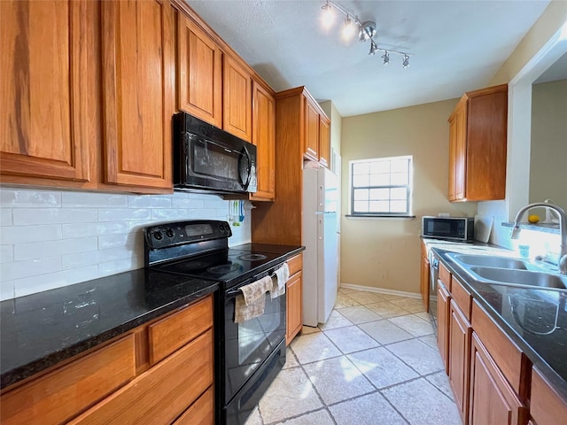 kitchen featuring black appliances, sink, decorative backsplash, dark stone countertops, and light tile patterned floors