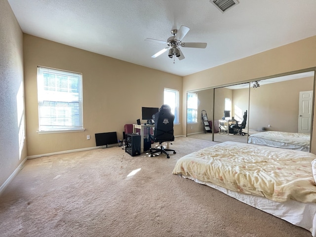 bedroom with a textured ceiling, ceiling fan, light carpet, and a closet