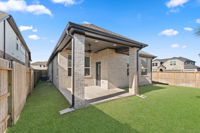 back of property with ceiling fan, a patio, a fenced backyard, brick siding, and a yard