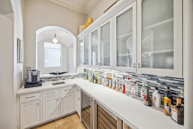 bar featuring sink, tasteful backsplash, crown molding, beverage cooler, and white cabinets