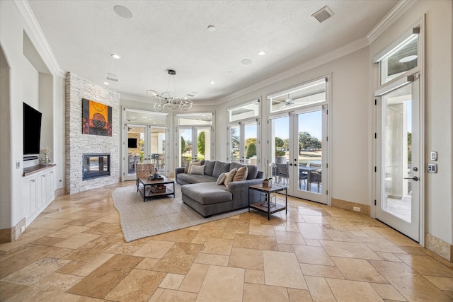 living room with french doors, an inviting chandelier, a textured ceiling, ornamental molding, and a fireplace