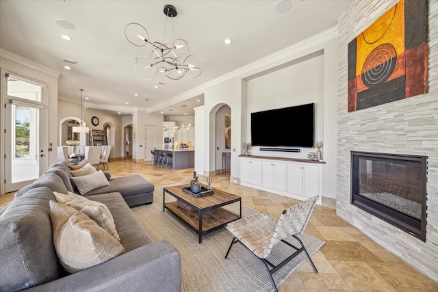 living room with crown molding, a fireplace, and an inviting chandelier