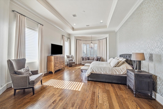 bedroom with hardwood / wood-style flooring, crown molding, and a raised ceiling