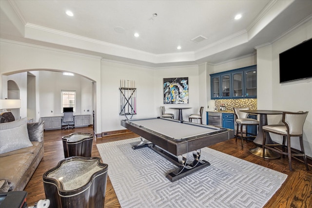 recreation room featuring ornamental molding, hardwood / wood-style floors, bar area, and a tray ceiling