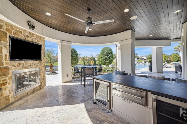 view of patio / terrace with wine cooler, ceiling fan, and an outdoor stone fireplace