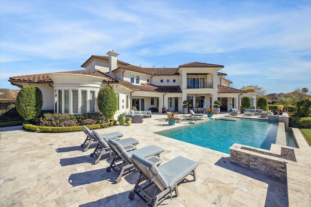 back of house featuring a balcony, outdoor lounge area, and a patio area