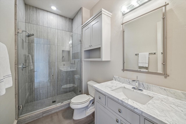 bathroom with vanity, a shower with door, and toilet