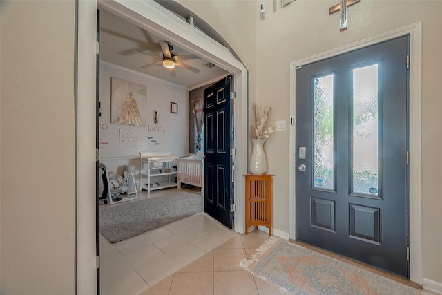 entryway with ceiling fan, crown molding, and light tile patterned floors