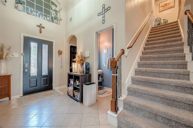 foyer entrance featuring light tile patterned floors and a high ceiling