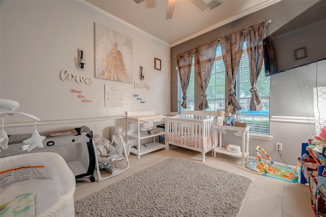 bedroom featuring a crib, tile patterned flooring, ceiling fan, and ornamental molding