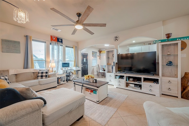 tiled living room featuring ceiling fan with notable chandelier