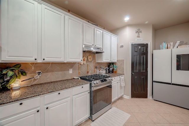 kitchen featuring white cabinets, white refrigerator, decorative backsplash, light tile patterned floors, and gas stove