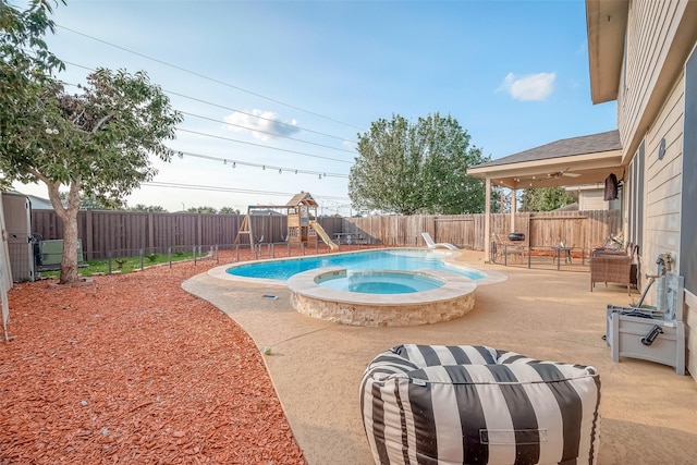 view of pool with a patio area, a playground, and an in ground hot tub