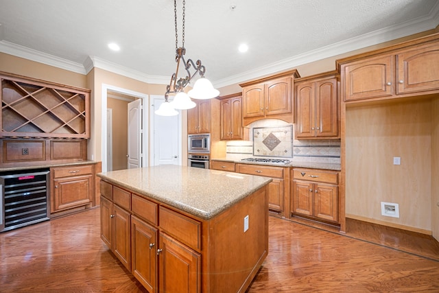 kitchen featuring appliances with stainless steel finishes, decorative light fixtures, wine cooler, hardwood / wood-style flooring, and a center island