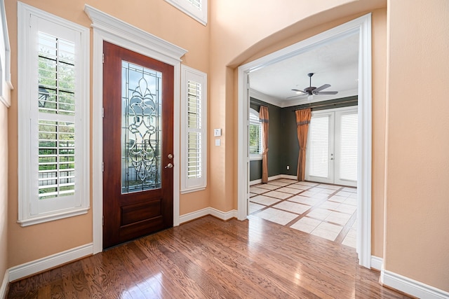 foyer with hardwood / wood-style flooring, ornamental molding, ceiling fan, and french doors