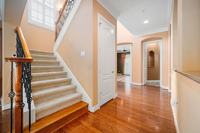 stairs with wood-type flooring and ornamental molding