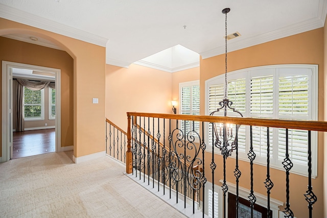 hallway featuring ornamental molding, light carpet, and a notable chandelier