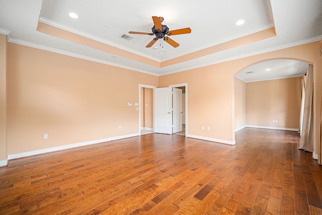 empty room with hardwood / wood-style flooring, ceiling fan, crown molding, and a raised ceiling