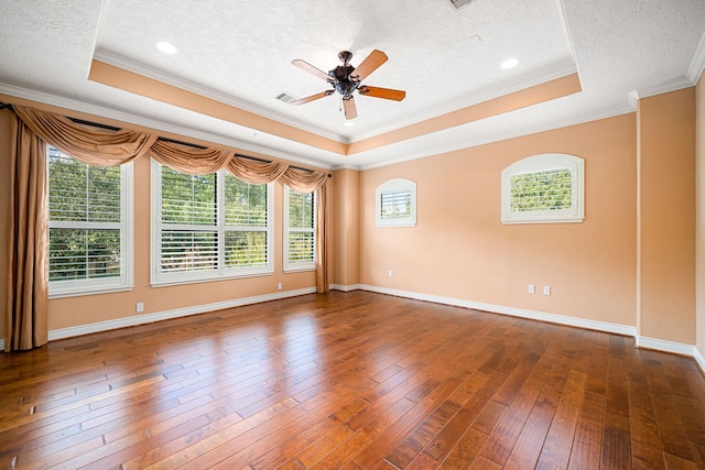 spare room featuring a raised ceiling, ornamental molding, dark wood-type flooring, and a textured ceiling