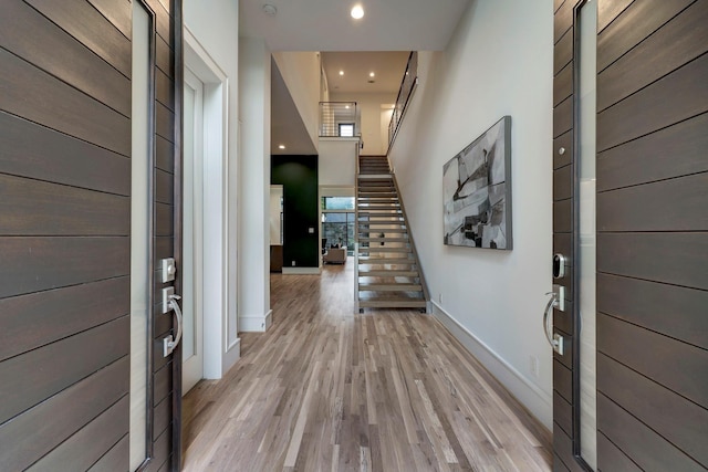 foyer entrance with light hardwood / wood-style flooring and a towering ceiling