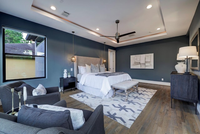 bedroom featuring dark hardwood / wood-style floors, a raised ceiling, and ceiling fan