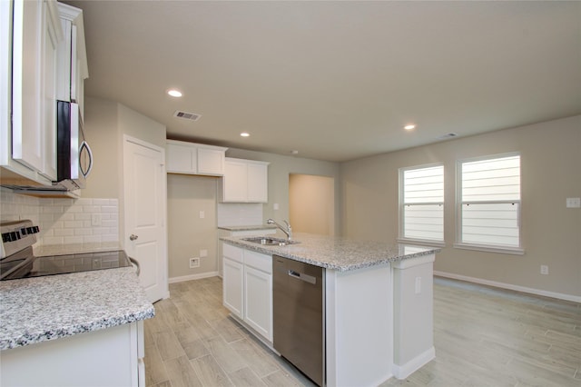 kitchen featuring white cabinetry, light stone countertops, an island with sink, and stainless steel appliances