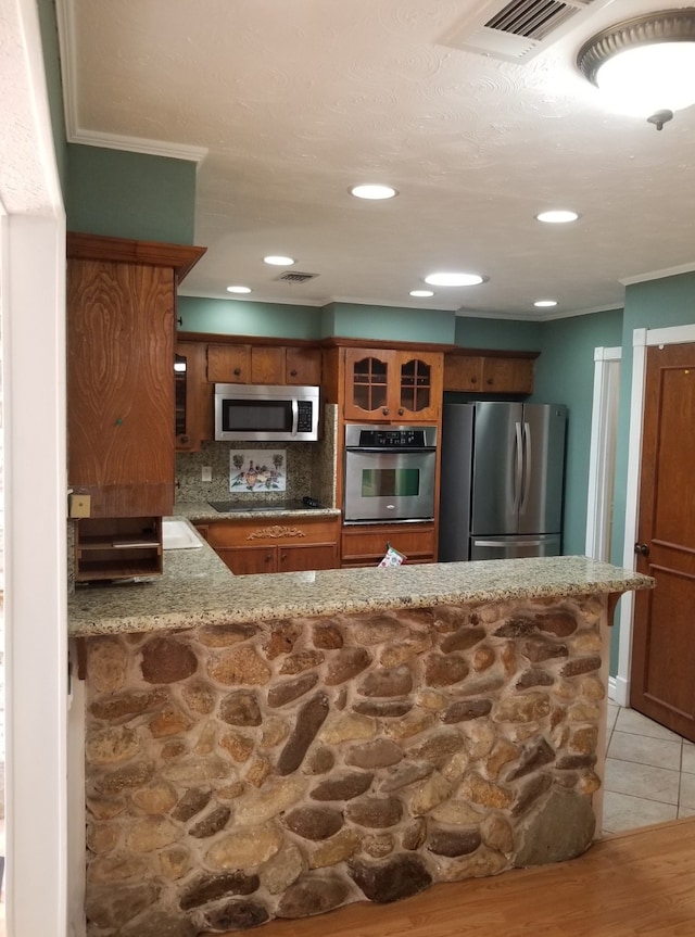 kitchen with kitchen peninsula, appliances with stainless steel finishes, backsplash, and ornamental molding