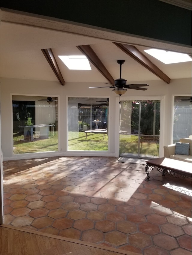 unfurnished sunroom featuring beamed ceiling and a skylight