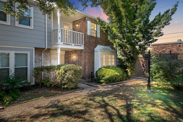 property exterior at dusk with a yard and a balcony