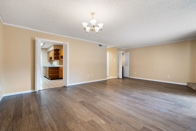 unfurnished room featuring an inviting chandelier, ornamental molding, a textured ceiling, and light hardwood / wood-style flooring