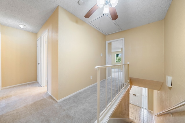 hall featuring a textured ceiling and light colored carpet