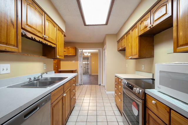 kitchen featuring sink, light tile patterned floors, a notable chandelier, and appliances with stainless steel finishes