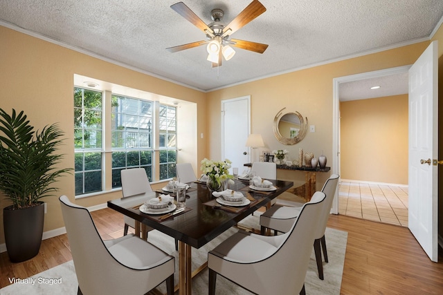 dining room featuring a textured ceiling, light wood-type flooring, ceiling fan, and crown molding